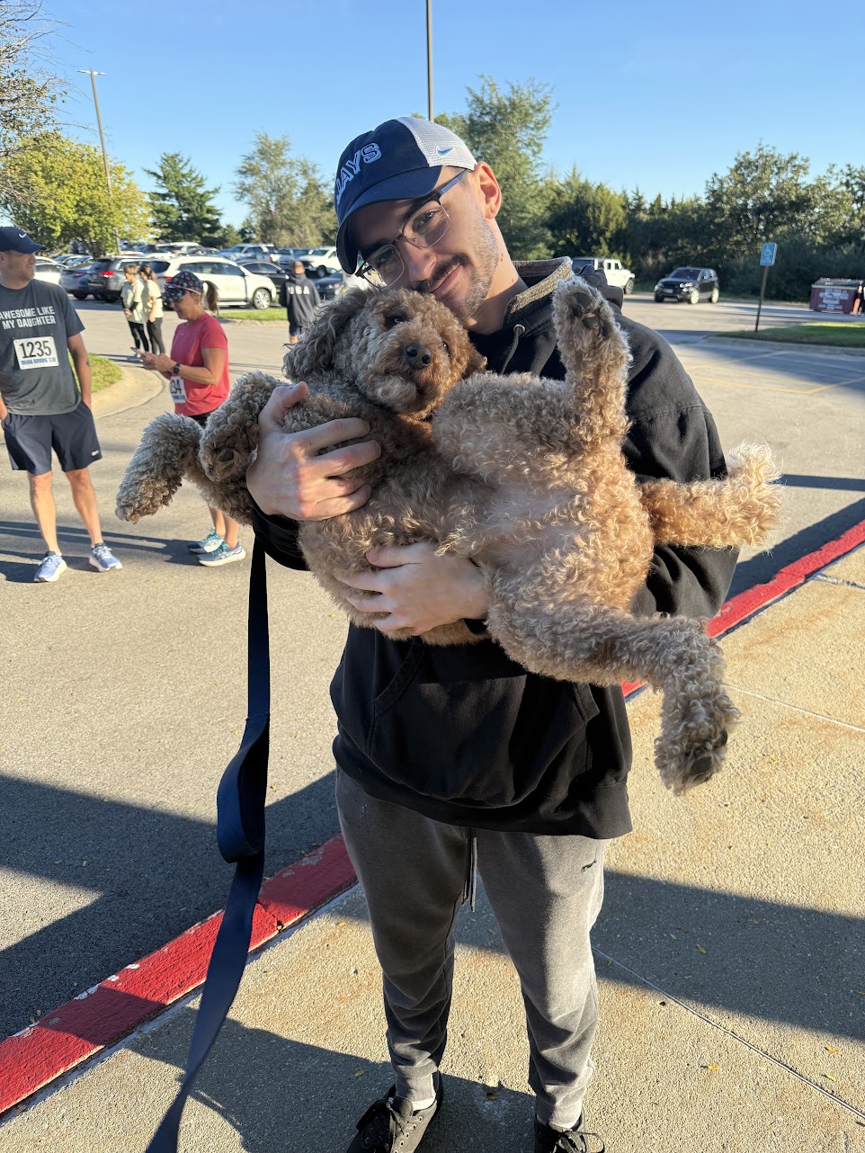 A person holding a dog outdoors at the race.